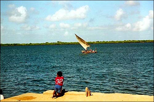 Boy watching dhow sail by -- Lamu, Kenya